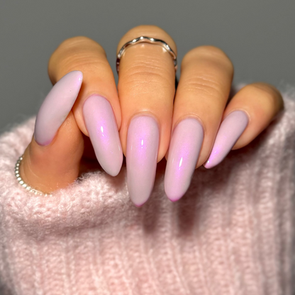 Hand with pink and purple gradient nails wearing a light pink sweater.